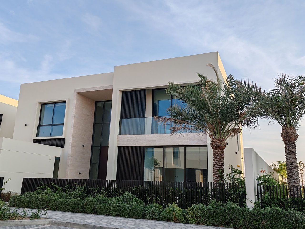 Modern two-storey villa in Dubai with palm trees and a landscaped front garden